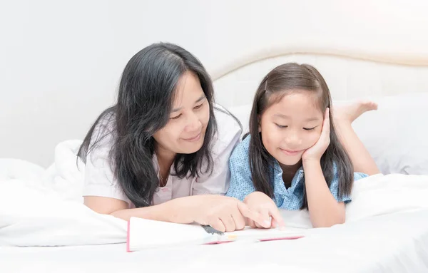 Madre e hija leyendo libro en la cama — Foto de Stock