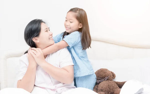 Lindo asiático chica sonrisa y abrazo madre en cama en la mañana — Foto de Stock