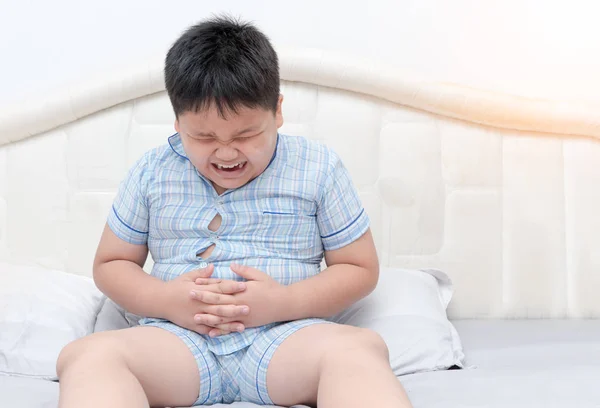 Obese boy overweight stomachache on bed — Stock Photo, Image