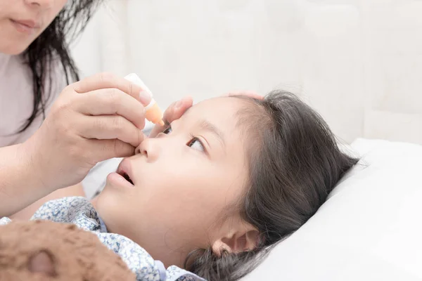 La madre gotea en los ojos de la muchacha la solución medicinal — Foto de Stock