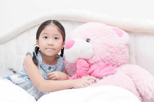 Lindo asiático niña jugando estetoscopio con teddy oso — Foto de Stock