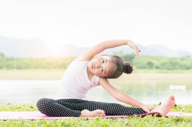sevimli kız pratik yoga poz bir mat Park