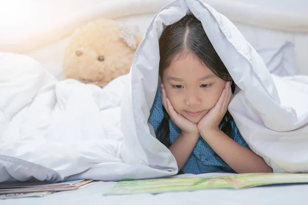 Carino poco asiatico ragazza lettura fiabe libro sotto coperta su — Foto Stock