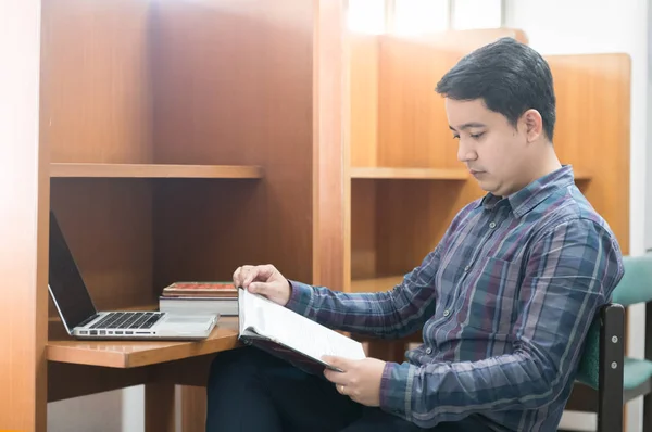 Азіатський студент чоловічої статі читає книгу в бібліотеці , — стокове фото