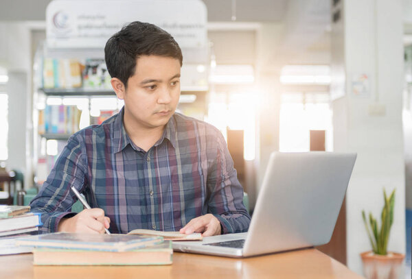 молодой студент, работающий с ноутбуком
 