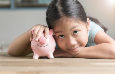 antika ahşap masa üzerinde bir kumbara ile şirin kız.