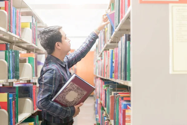Fiatal diák könyv-ra könyvespolc található könyvtár — Stock Fotó