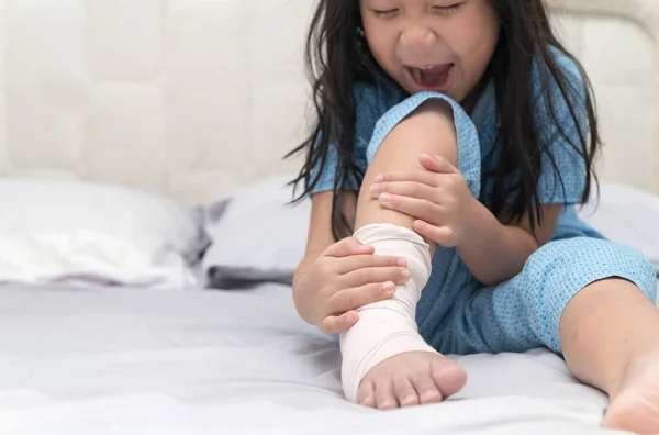 Τον πόνο ποδιών. Μικρό παιδί με σπασμένο πόδι στο κρεβάτι, — Φωτογραφία Αρχείου