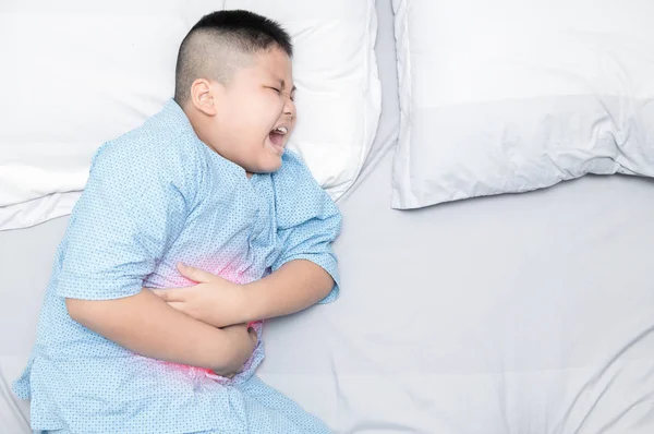 Jongen lijden buikpijn op bed — Stockfoto