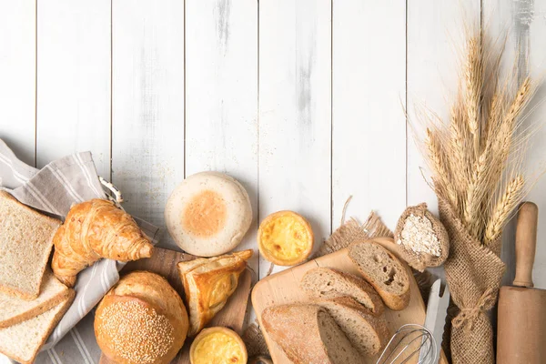 Хлеб и хлебобулочные ингредиенты на белом дереве — стоковое фото