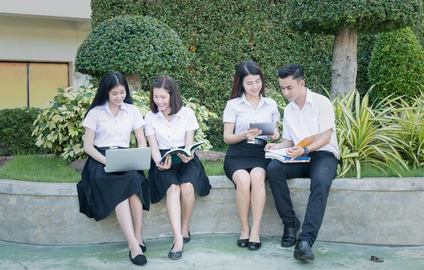 Jovens estudantes jogar computador e leitura livro na universidade — Fotografia de Stock