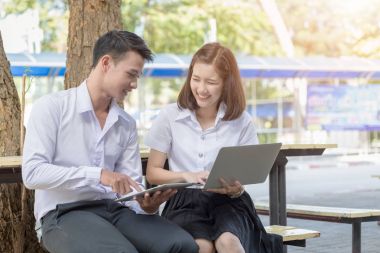 İki genç öğrenci üniversite sandalyede tablet ve dizüstü oynamak
