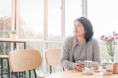 Düşünceli genç kadın kahve dükkanında pencereden arıyor