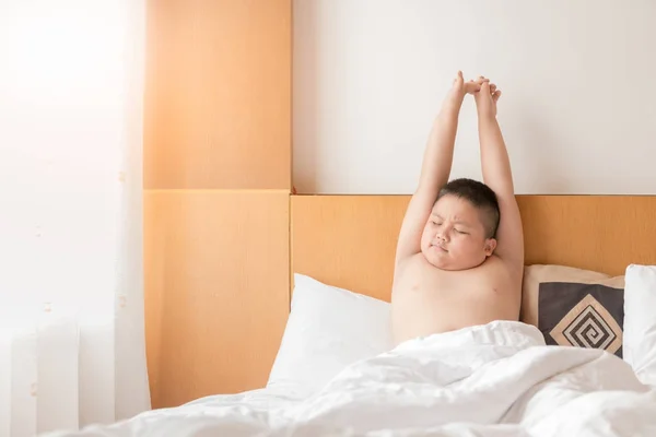 Anak gemuk gemuk bangun dan berbaring di tempat tidur di pagi hari — Stok Foto