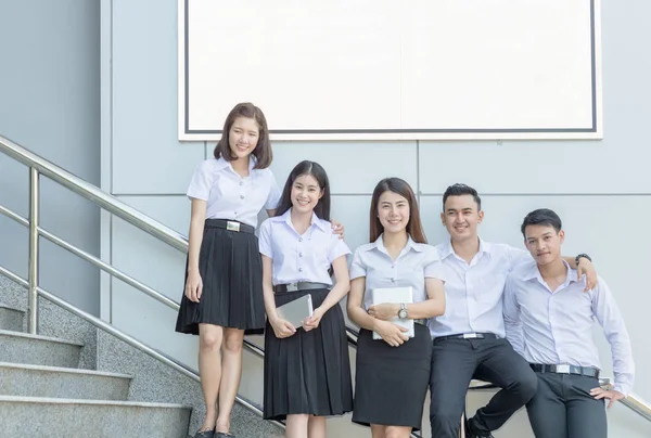 Студенты стоят и улыбаются на лестнице с белым рекламным щитом — стоковое фото