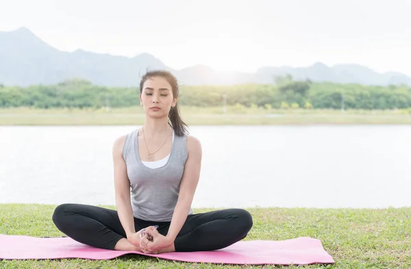 Attractive young woman exercising and sitting in yoga