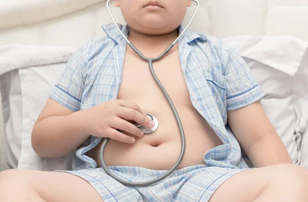 Zwaarlijvige vet jongen controleren maag door stethoscoop. — Stockfoto