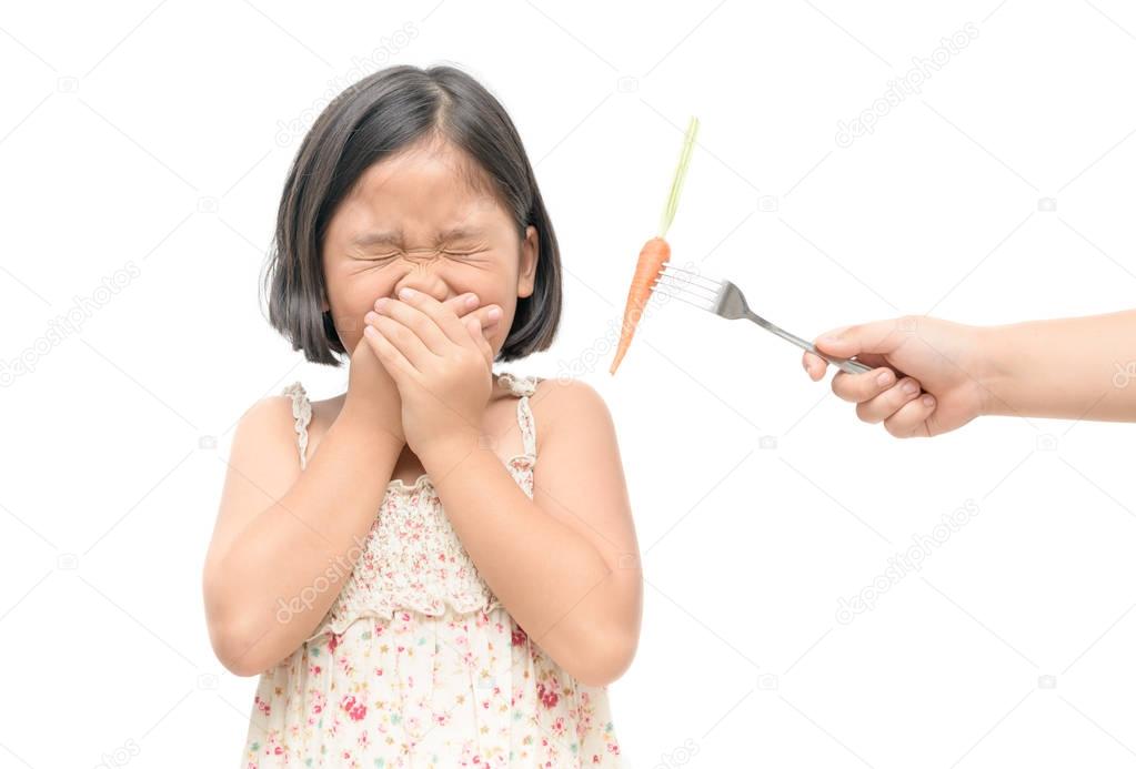 asian child girl with expression of disgust against vegetables 