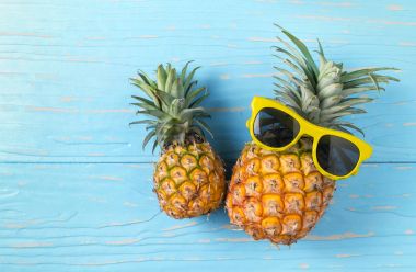 Ananas mavi ahşap arka plan üzerinde güneş gözlüğü ile