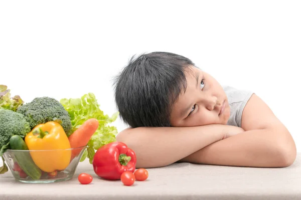 Menino com expressão de nojo contra legumes — Fotografia de Stock