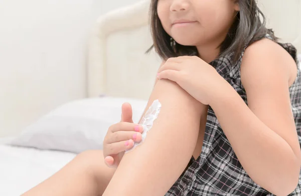 Cute girl applying  body lotion on her leg. — Stock Photo, Image