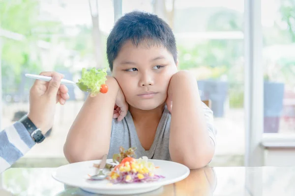 Niño obeso con expresión de disgusto contra las verduras — Foto de Stock
