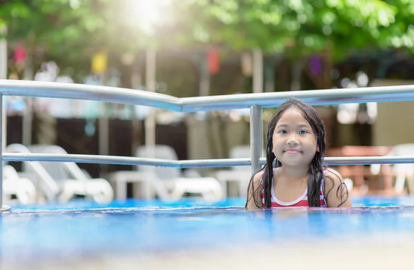 Söpö aasialainen tyttö pelata vettä uima-altaassa — kuvapankkivalokuva