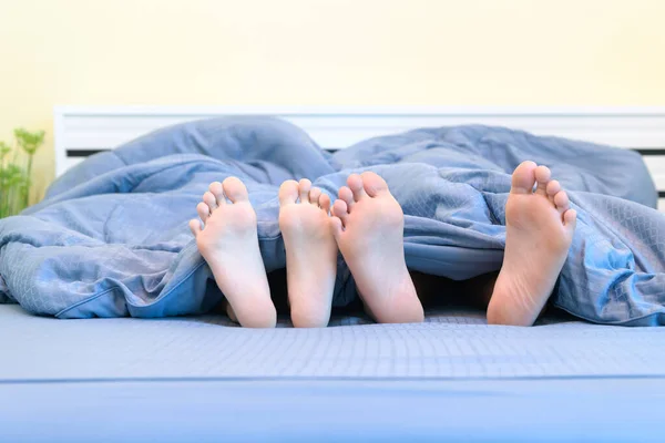 Dua pasang kaki anak-anak. Kakak dan adik terbaring di bawah selimut — Stok Foto