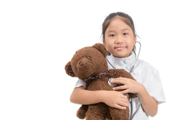 Kind in doktersjas met stethoscoop onderzoek teddybeer — Stockfoto