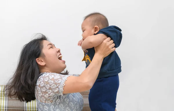 Vista lateral de madre asiática levantando y jugando con bebé recién nacido , — Foto de Stock