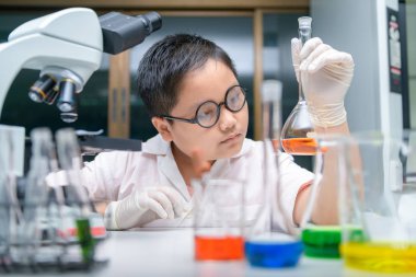 Çocuk bilim adamı kimya laboratuvarında deney yapıyor., 