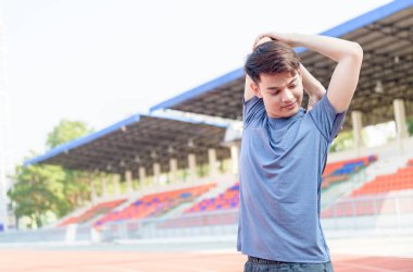 Genç Asyalı adam koşmadan önce kollarını açıyor. 