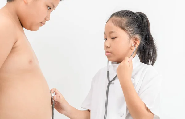 Pequeno médico está verificando o estômago menino gordo com um estetoscópio em — Fotografia de Stock