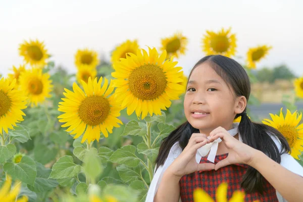 Linda chica asiática mostrando símbolo de signo de corazón y sonrisa con flujo de sol —  Fotos de Stock