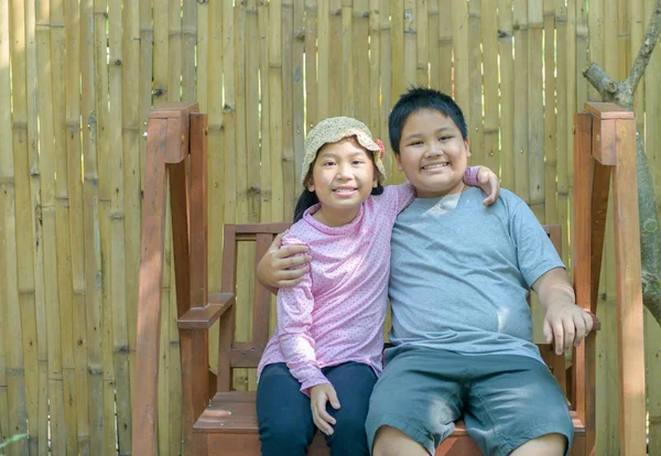 Feliz hermano y hermana sonrisa y sentarse en swing . — Foto de Stock