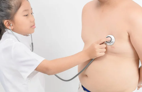 Il piccolo medico controlla il cuore dallo stetoscopio al ragazzo obeso — Foto Stock