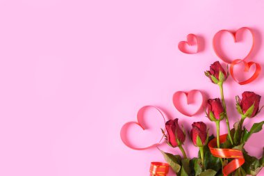 Pembe arka planda kırmızı güller ve kalp kırmızı kurdele, 