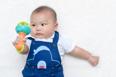 Bebek oyuncak oynar ve yün üstünde yatar., 