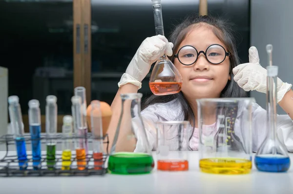 Happy little girl wearing lab coat making experiment — Stock Photo, Image