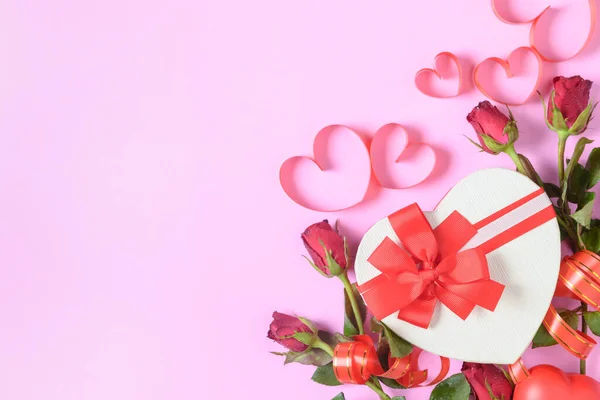 Red roses and gift box with heart red ribbon on pink background, — Stock Photo, Image