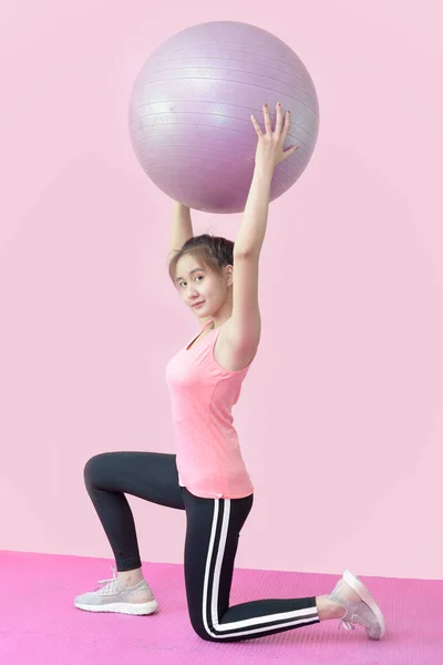 Χαριτωμένη Ασιάτισσα κάνει γυμναστικές ασκήσεις με μπάλες . — Φωτογραφία Αρχείου