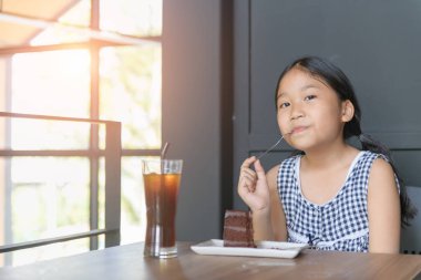 kid enjoy eating chocolate and and ice tea in coffee shop, 