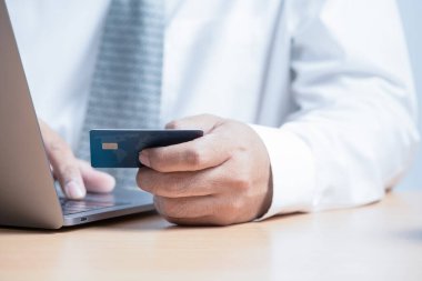Kredi kartı tutan ve dizüstü bilgisayar kullanan bir iş adamı. Çevrimiçi alışveriş kavramı