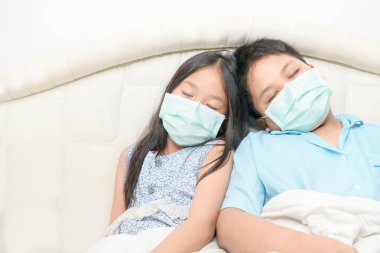 Erkek ve kız kardeş cerrahi maske takıyor yatakta uyuyor, Wuhan Coronavirüs ve salgın virüsü olan hasta çocuk. Coronavirüs veya covid-19 konsepti.