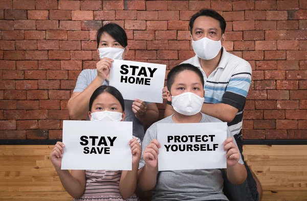 Asian  Family wear mask and shows paper with stay home stay save words at home, Coronavirus, COVID-19, self-quarantine, social disdancing concept.