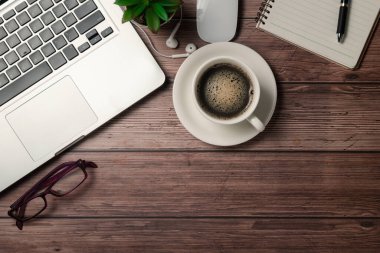 Sade kahve, dizüstü bilgisayar, defter ve gözlüklü eski ahşap masa. Kopyalama alanı olan üst görünüm, düz yatay.
