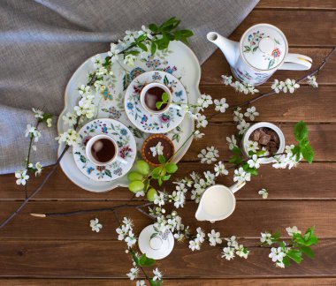 Kahve fincanları çiçekli masada.