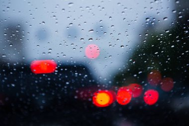 Işıkların arka planında bardaktaki yağmur damlaları