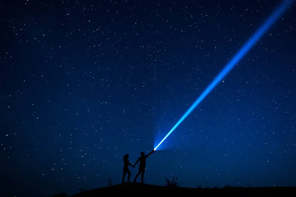 Couple in love walks under the stars. Silhouette of lovers couple who are enjoying their time together at night under a starry sky. Starry sky. Night walk. Man and woman traveling