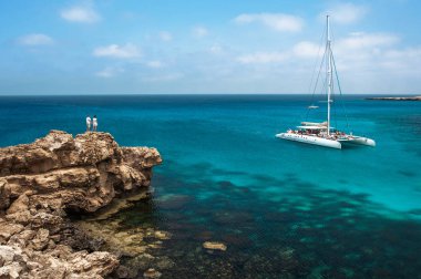 Denizin kenarında uçurumdaki seven çift lagün görünüyor. Balayı severler. Erkek ve kadın adada. Çift tatilde aşık. Bir cruise gezisi için bir fiş. Deniz turu. Balayı gezisi